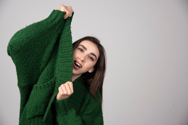 Young woman pulling her sweater on gray.