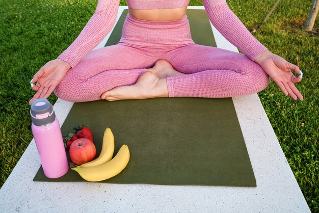 young woman in purple shirt and trousers on the grass during daytime inside green park meditating