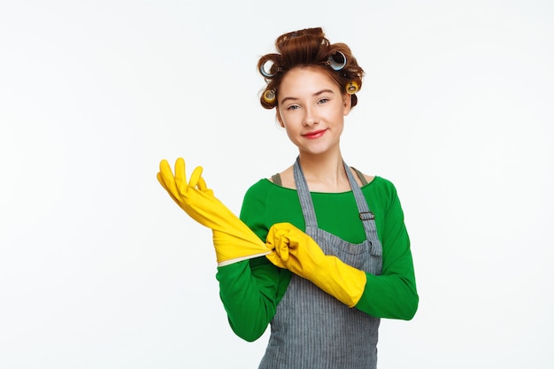 Young woman puts in rubber gloves with curlers on hair