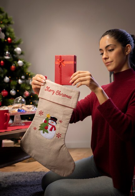 Молодая женщина кладет подарки в гигантские носки