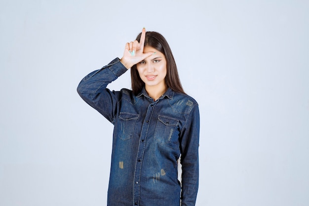 Young woman putting hand to her forehead and showing loser sign
