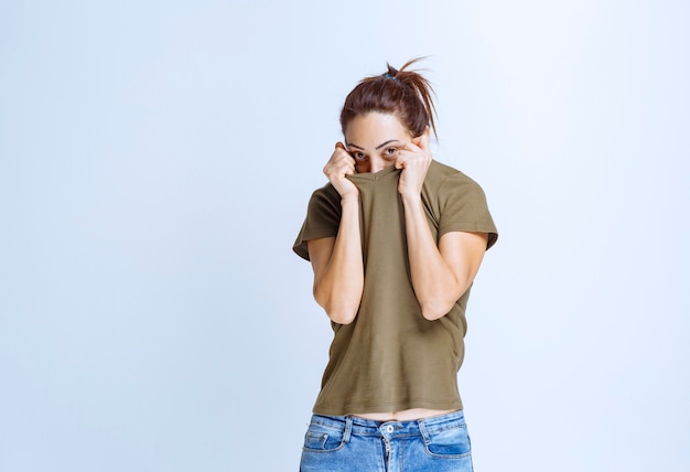 Young woman putting hands to her face and looks terrified and scared