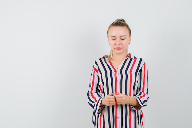 Free photo young woman putting her one hand on hip in striped blouse