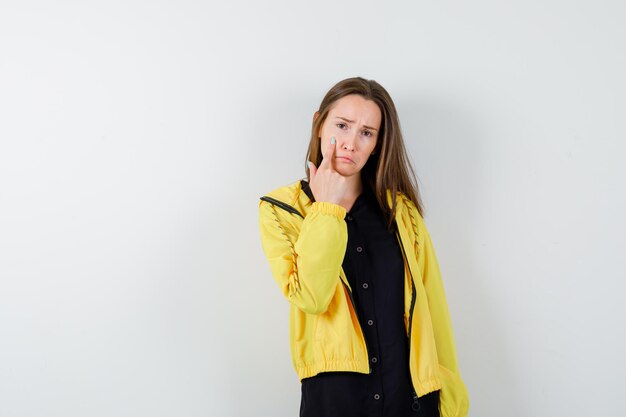 Young woman putting index finger on cheek