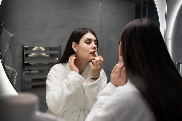 Free photo young woman putting on make-up in a hotel bathroom