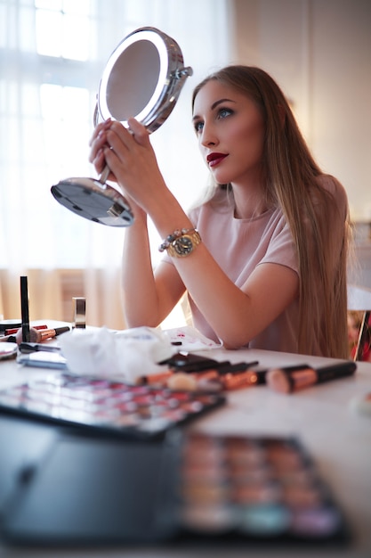 Free photo young woman putting on makeup