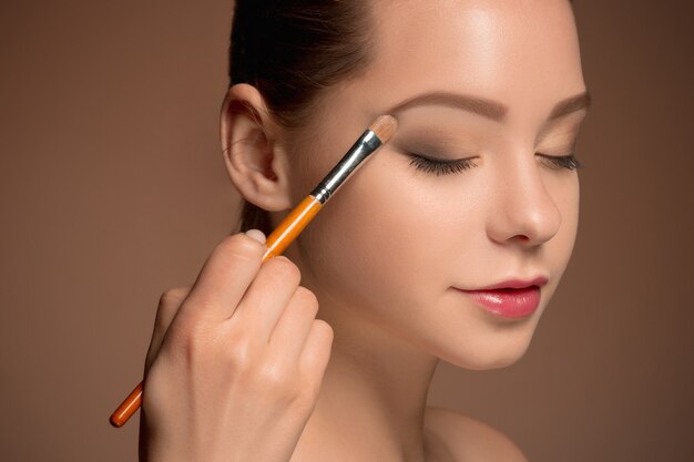 Young woman putting makeup on