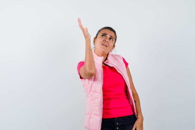Young woman raising hand above in pink t-shirt and jacket and looking beautiful