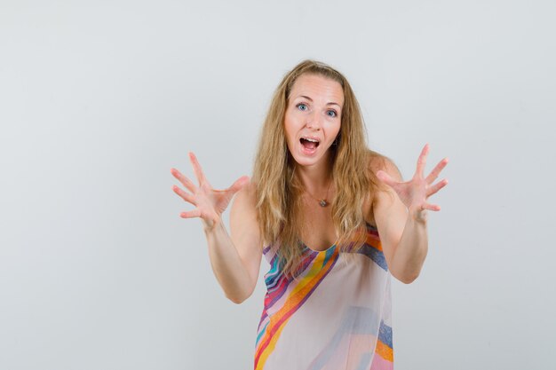 Young woman raising hands as catching something in summer dress and looking happy. 