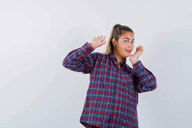 チェックシャツで降伏ポーズで手を上げてきれいに見える若い女性