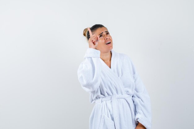 Young woman raising index finger in eureka gesture