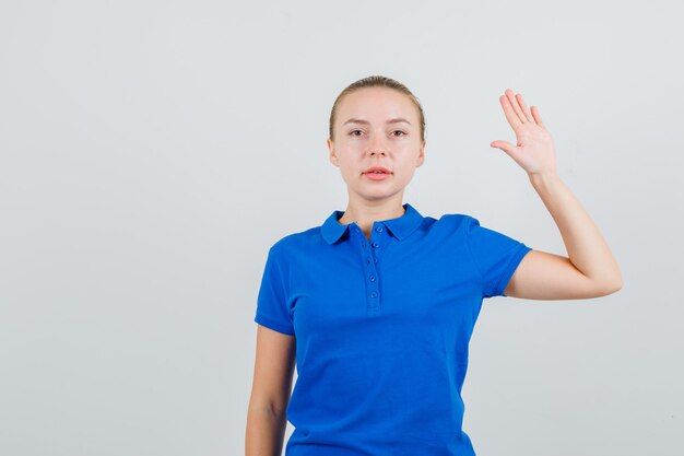 青いTシャツで手のひらを上げて自信を持って見える若い女性