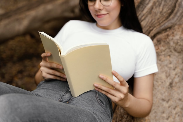 無料写真 屋外で面白い本を読んでいる若い女性