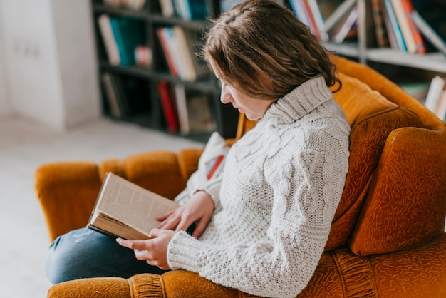 Free photo young woman reading in armchair