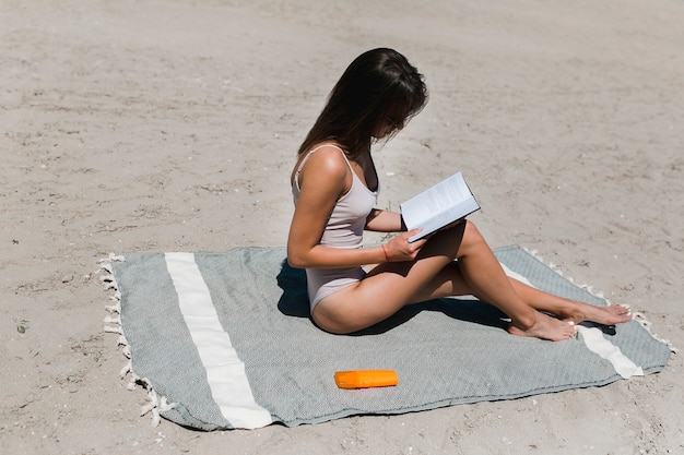 ビーチで読書する若い女性