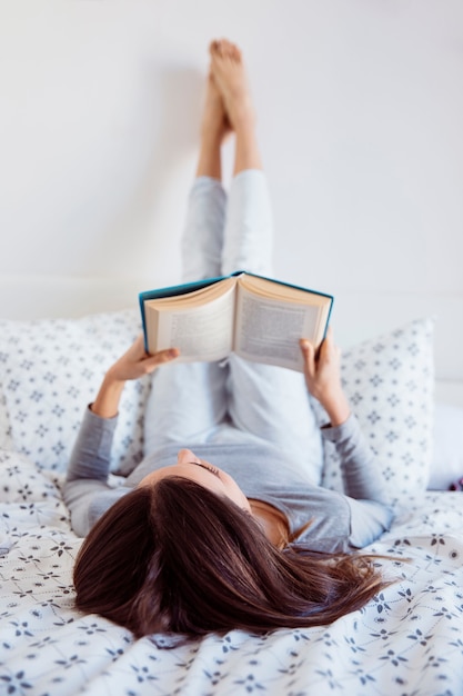 침대에서 독서하는 젊은 여자