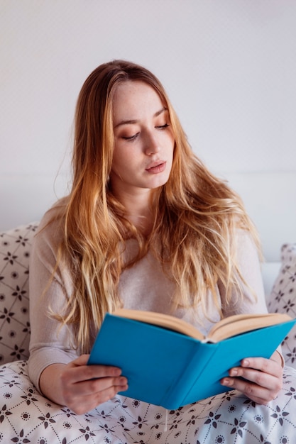 Free photo young woman reading in bed