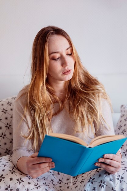 Young woman reading in bed 