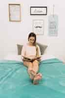 Free photo young woman reading on bed