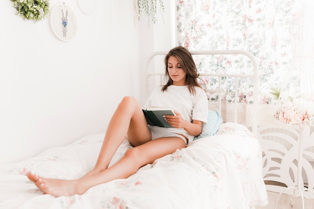 침대에서 책을 읽는 젊은 여자