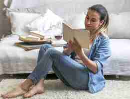 Foto gratuita giovane donna che legge un libro in una stanza accogliente