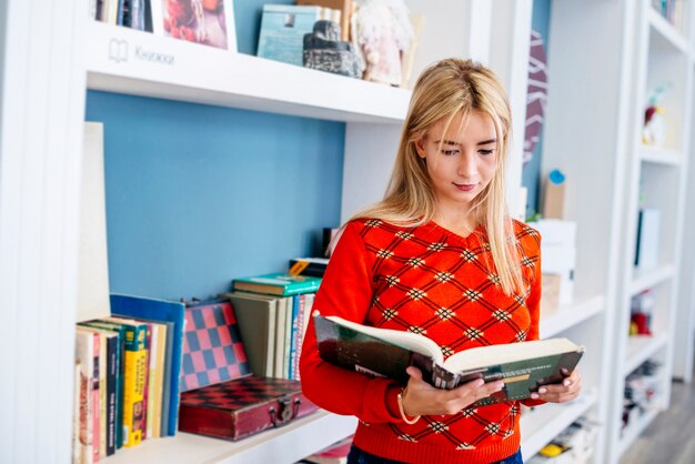 young woman reading book in library