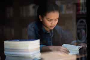 Free photo young woman reading book sitting indoor in urban cafe.