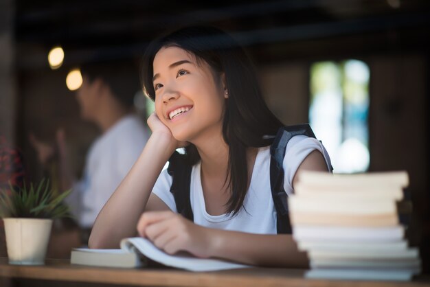 Young woman reading book sitting indoor in urban cafe.