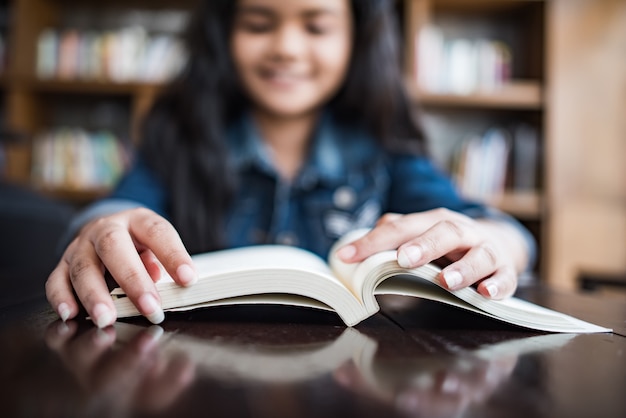 Young woman reading book sitting indoor in urban cafe.