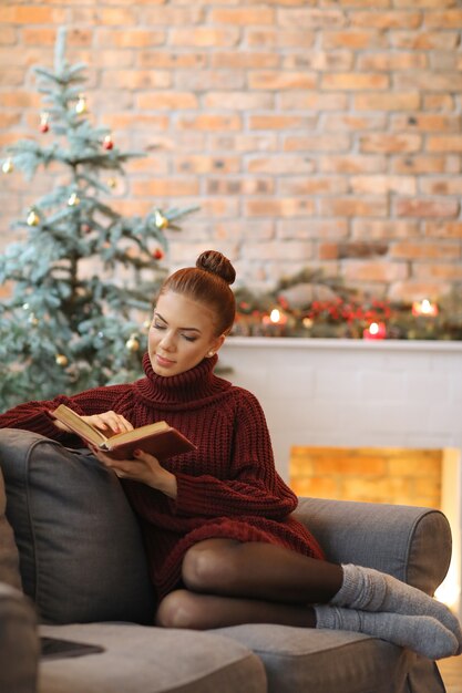 Young woman reading a book in the sofa