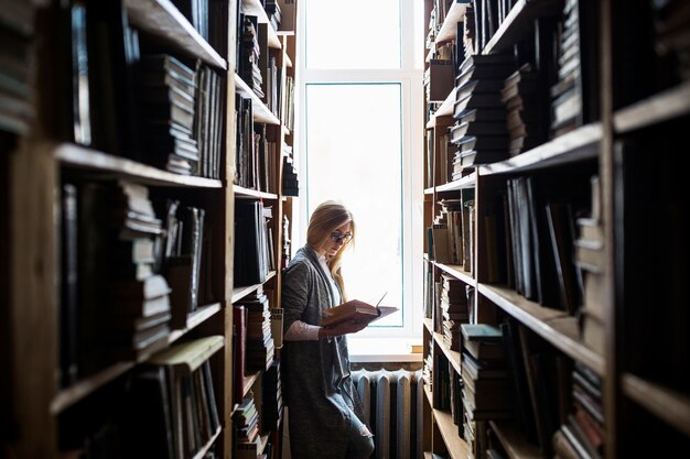 Young woman reading between bookcases