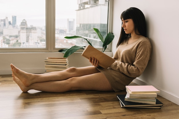 Foto gratuita giovane donna che legge sul pavimento