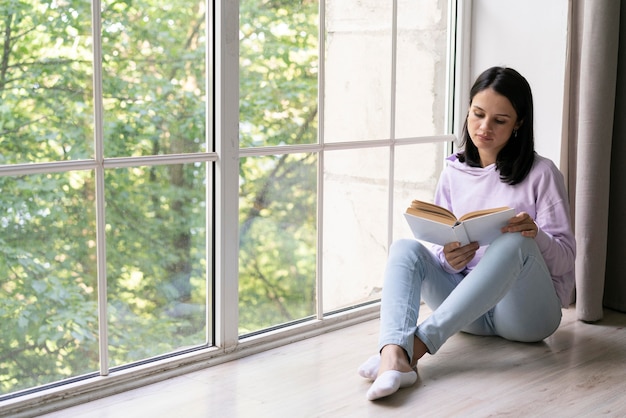 Free photo young woman reading from a book at home