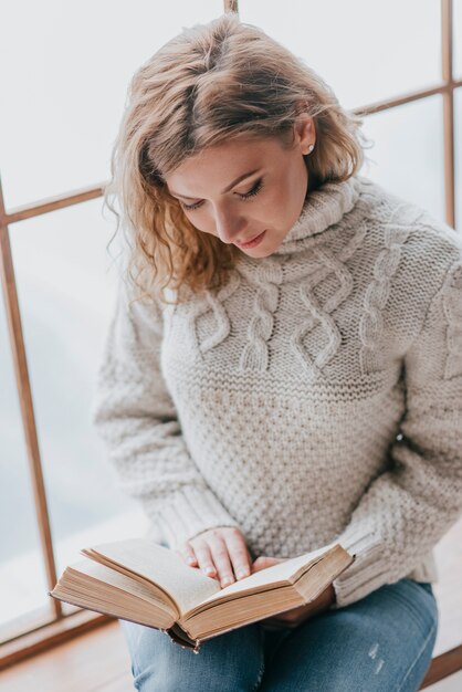 Young woman reading near huge window