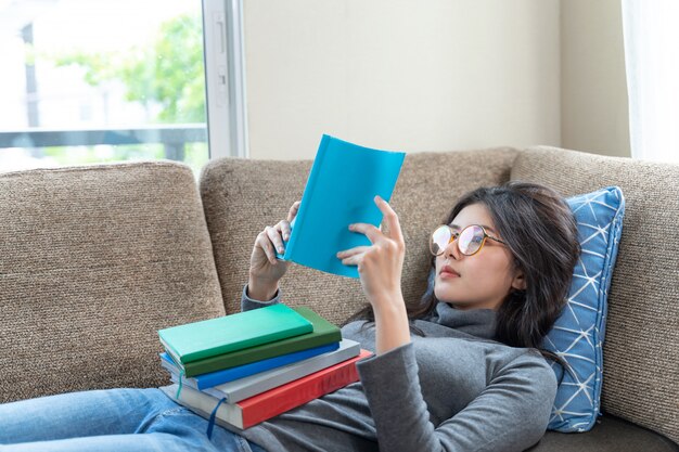 Young woman reading textbook on couch at home