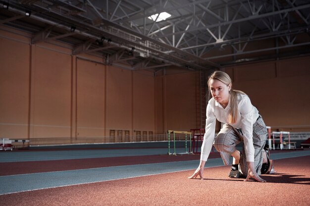 Young woman ready to run in suit full shot