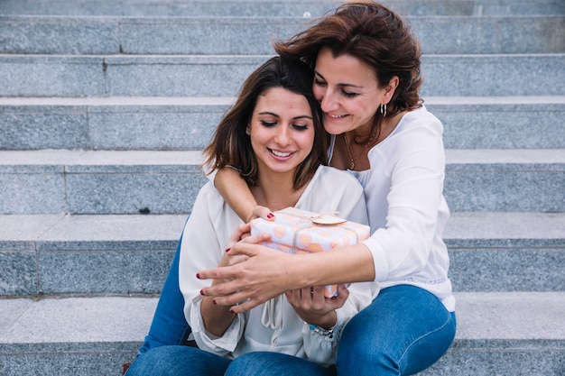 Free photo young woman receiving gift from mother