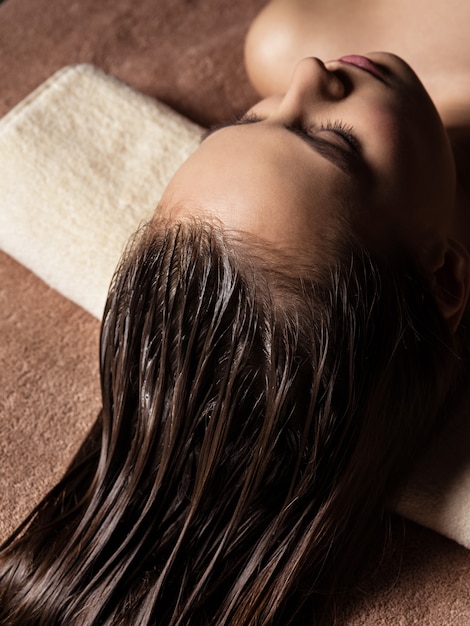 Foto gratuita giovane donna che riceve procedura di cura dei capelli nel salone della stazione termale. trattamento di bellezza. salone della stazione termale