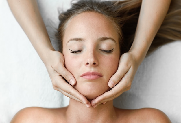 Young woman receiving a head massage in a spa center.