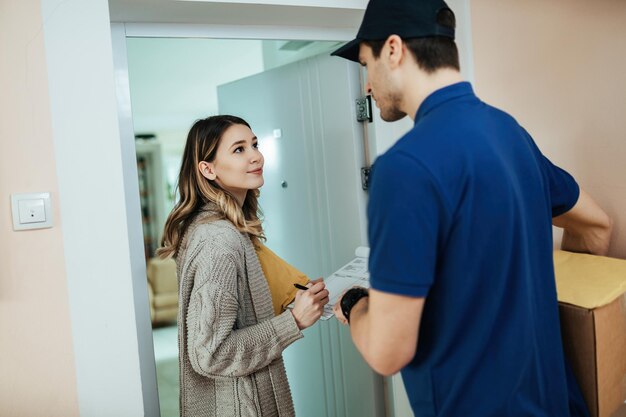 Young woman receiving home delivery and signing documents to a courier