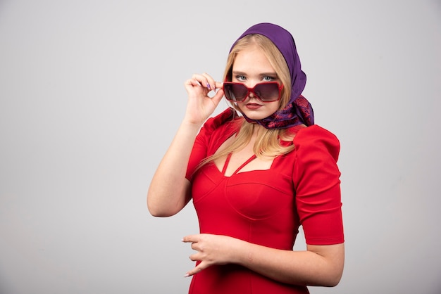 Young woman in red outfit posing on gray background. 