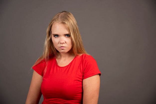 Free photo young woman in red shirt posing on black wall.