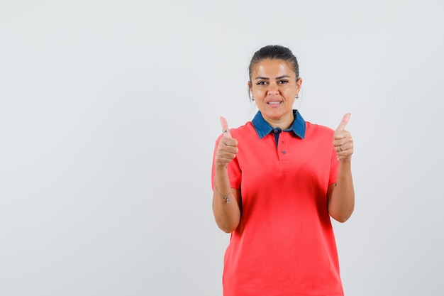 Young woman in red shirt showing double thumbs up and looking pretty , front view.