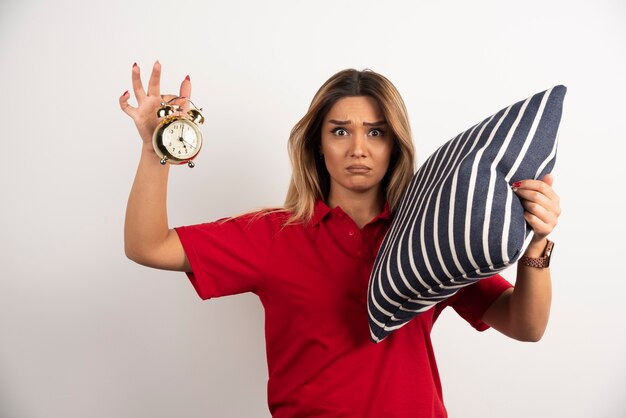 Young woman in red short holding pillow and clock .