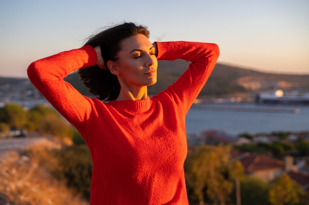 Giovane donna con un maglione rosso in un magnifico tramonto sulla montagna