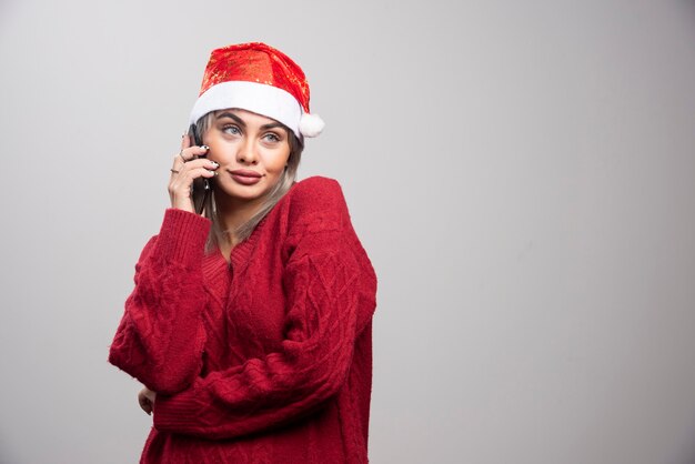 携帯電話で話している赤いセーターの若い女性。