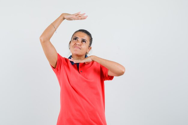 Young woman in red t-shirt showing traditional dance gesture and looking pretty , front view.