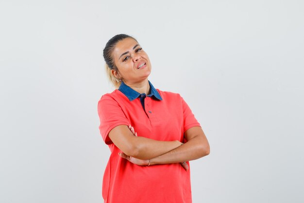 Young woman in red t-shirt standing arms crossed and looking confident , front view.
