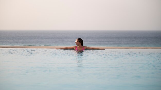 Молодая женщина отдыхает в одиночестве в бассейне