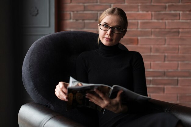 Free photo young woman relaxing on couch with magazine